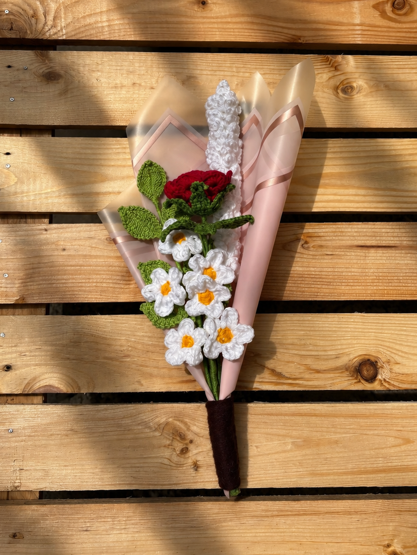 Bouquet of flowers wrapped in pink paper on a wooden surface