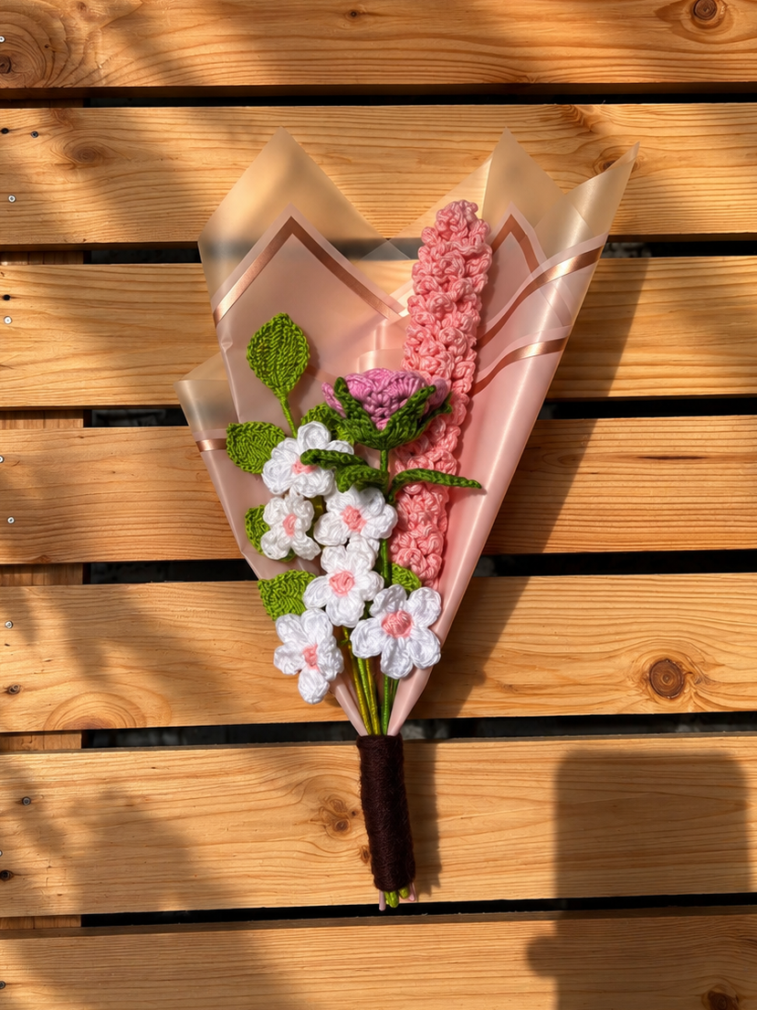 Bouquet of flowers wrapped in pink paper on a wooden surface
