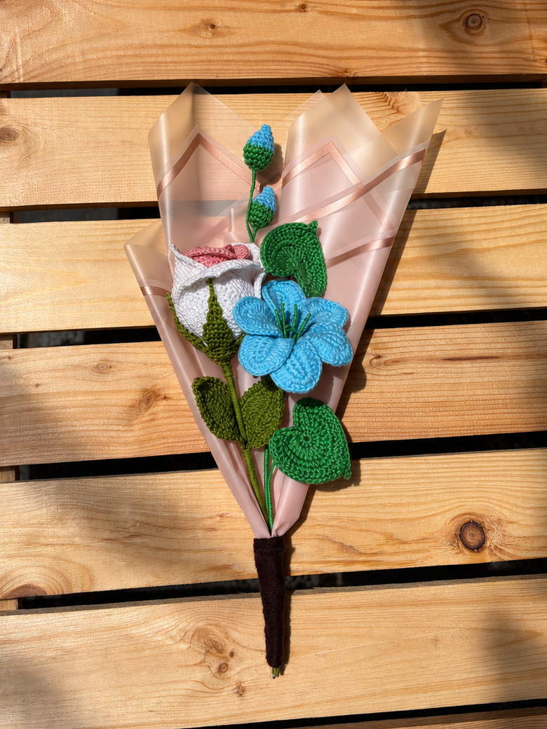 Decorative flower arrangement with blue center and green leaves on a wooden surface